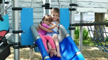 Aktif ve neşeli çocuklar oyun bahçesinde oynuyorlar ve sarılıyorlar.