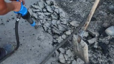 Yol işçisi, asfaltı kaya matkabıyla parçaladı ve eski asfaltı kürekle tırmıkladı.