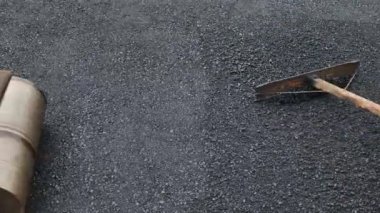 Yol yapım ekibi yeni bir kaplama için asfaltı düzleştirmek için kürek ve paspas kullanıyordu.