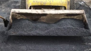 Yol yapım ekibi inşaat alanında yeni asfalt dağıtmak için kürek kullanıyor.