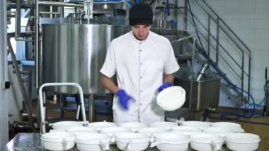 Eldivenli bir işçi, bir mandıra fabrikasında süzme peynir üretme sürecini gösteriyor.