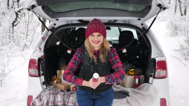 若い美しい女性は雪の森の中の車のトランクに座っていて 蛇紋岩で爆竹を爆発させています 欠陥のある爆竹 — ストック動画