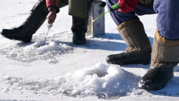 在结冰的湖上钓鱼两个人一起钓鱼冰洞和冬季道路 — 图库视频影像
