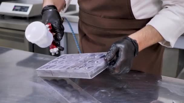 チョコレートを作るときに台所でペストリーエアブラシで食品塗料を噴霧男性ペストリーシェフの手のクローズアップ — ストック動画