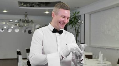 Beyaz gömlekli ve papyonlu bir garson bir sipariş yazar ve restoranda güler..