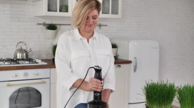 Kadın taze meyve, filizlenmiş buğday filizleri ve blender içinde çim çırpar..