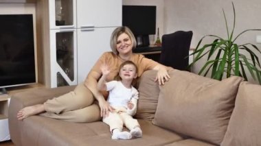 Kolu kırık küçük bir kız ve annesi kanepede oturmuş sarılıyorlar. mutluluk ve eğlence.