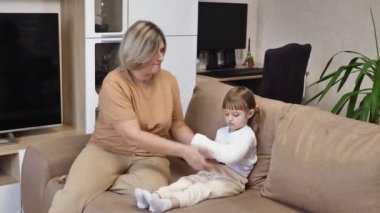 Anne, kızının kırık koluna bandaj sarar. Alçıtaşı.