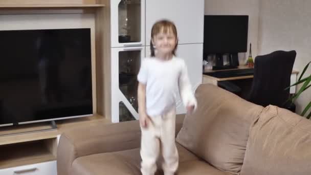 Cute Zabawna Dziewczynka Złamanym Ramieniem Gipsie Zabawy Skacze Kanapie — Wideo stockowe