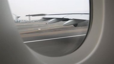 Uçak piste iniyor. Uçağın kanadı pencerede.