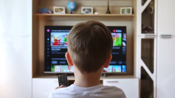 小男孩坐在沙发上 换了个电视频道 — 图库视频影像