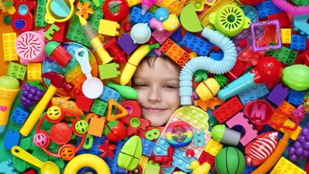 Zabawny Chłopczyk Leżący Chaosie Zabawek Twarz Dziecka Otoczona Klockami Zabawkami — Wideo stockowe