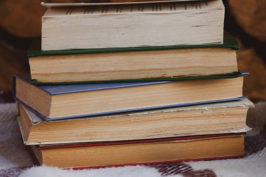 Yünlü battaniyenin üzerindeki eski kitap yığınını ahşap arka planda klasik tarzda kapat.