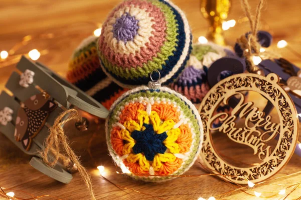 crocheted decorations for the Christmas tree. Bright balls with different crochet pattern of colored lace.  Wooden background and led lights