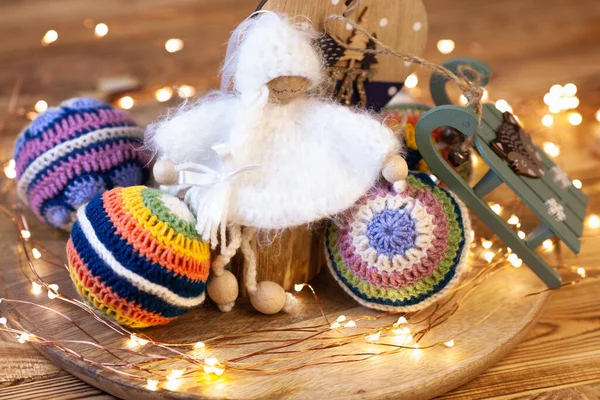 toy crocheted Christmas angel Christmas tree decoration surrounded by colorful balls and Christmas led lights
