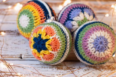 Noel ağacı için tığ işi süslemeler. Farklı renkli dantelli, parlak toplar. Beyaz ahşap arka plan ve yol gösteren ışıklar