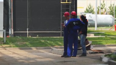 ALMATY, KAZAKHSTAN - 26 Ekim 2022: Taskmaster üretim tesisi yakınındaki inşaatçılarla ağır çekim konuşuyor. Foreman, 26 Ekim 'de Almaty' deki fabrikada çalışan işçilere talimat veriyor.