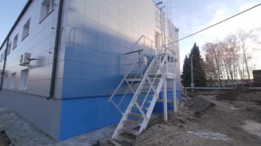Kış günü endüstriyel bina duvarında metal acil durum merdiveni var. Aşırı kazalar için atölye güvenlik ekipmanı