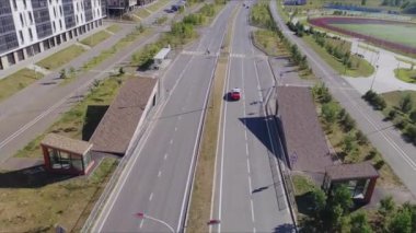 Güneşli bir günde, konut bölgesinde yaya geçidi olan boş yolda otomobil sürüyor. Çağdaş şehir yaşam tarzı