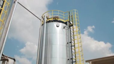 Karbon fiber üretim fabrikasında servis merdivenleri olan yuvarlak metal tanklar. Avludaki malzeme işleme konteynerleri
