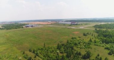 Büyük yeşil alan ve bulutlu gökyüzünün altındaki depo binaları yaz günü kuş bakışı. Kırsal alan