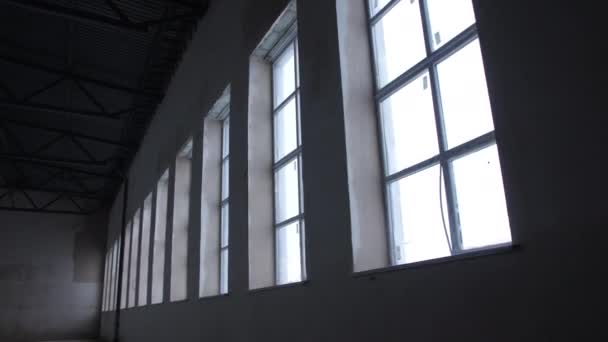 未完成のワークショップの建物の壁に高い窓の行 生産工場内からの眺めの建設現場 — ストック動画