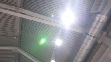 Endüstriyel hangarın yarım daire tavanında parlayan lambalar ve havalandırma borusu. Yapılanmada iletişim