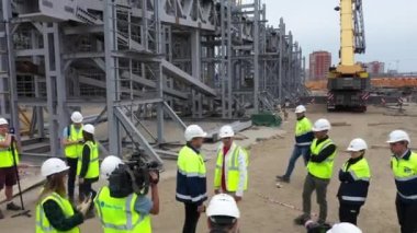 ALMATY, KAZAKHSTAN - 10 Ağustos 2022 Foreman stadyum inşaatında müfettiş olarak ilerleme kaydettiğini gösteriyor. Gazeteciler 10 Ağustos 'ta Almaty' de gelecekteki spor sahasında çalışıyorlar