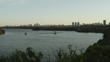 Su temizleme teknesi günbatımı kuşbakışı manzaralı çağdaş şehre karşı sakin gölde çalışır. Ekoloji koruma tesisi