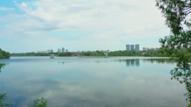 Su temizleme tekneleri, yaz günü kuş bakışı manzaralı çağdaş şehre karşı yeşil bankayla sakin nehirde çalışır.