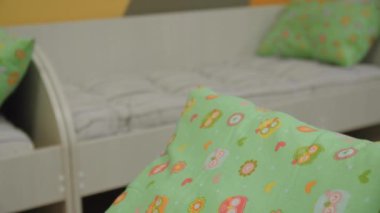 Çağdaş anaokulunun yatak odasındaki küçük yataklarda çocuk desenleri olan yastık. Çocukların uyuyacağı bir yer.
