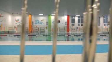 Temiz suyla yüzme havuzu ve duvarlarda metal çitlerin ötesine bakan resimler. Eğlence ve eğitim için spor kompleksi