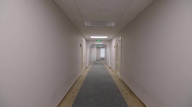 Çağdaş şirket binasında ofis kapıları olan uzun ışık koridoru. Şirketin minimalist iç tasarımı