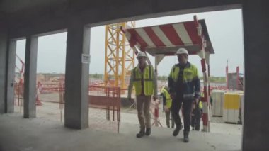 ALMATY, KAZAKHSTAN - 07 Eylül 2022: Mühendis ve atış ekibi tamamlanmamış spor kompleksi binasına girer. İnşaat alanı yavaş çekim Almaty 07 Eylül