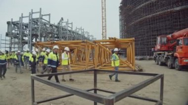 ALMATY, KAZAKHSTAN - EPTEMBER 07 2022: Ustabaşı ve kameramanla birlikte bir grup inşaatçı spor kompleksi şantiyesi boyunca yürüyor. Eylül 07 'de Almaty' de endüstriyel nesne denetimi