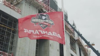 ALMATY, KAZAKHSTAN - 07 Eylül 2022: Kasvetli bir günde stadyumun inşaat alanında Avangard inşaat şirketi logosunun dalgalanması. Şirket sembolü 07 Eylül 'de Almaty' de