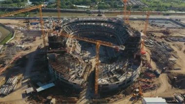 Şehir kuş bakışı manzaralı inşaat alanında yüksek vinçleri olan gelecekteki spor stadyumu binası. Kentsel mimari gelişimi