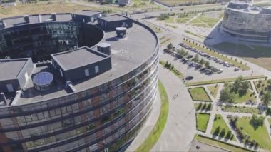 Güneşli şehir kuşbakışı manzaralı cam cepheli dairesel ticari bina. Şehir merkezindeki büyük ofis.