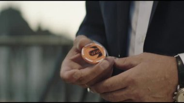 ALMATY, KAZAKHSTAN - AUGUST 22 2022: Businessman in formal suit tosses orange plastic chip for luck on blurred background closeup. Victory prediction on August 22 in Almaty