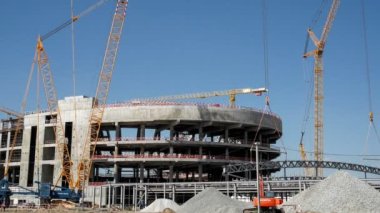 Timelapse of powerful cranes operation with carcass part at future sports arena construction site on sunny summer day