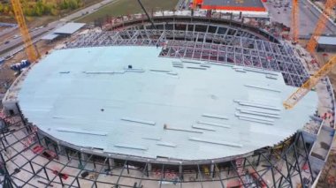 Sports stadium roof assembling with yellow tower cranes in city aerial view. Construction industry and technology