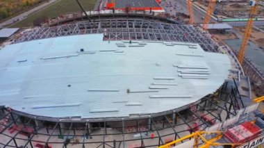 Sports stadium building progress and different operating cranes in modern city aerial view. Construction site technology