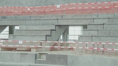 Concrete ground for spectator places with safety striped fences at future sports stadium construction site. Athletic arena