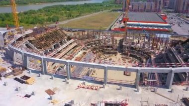 Construction site of innovative sports arena near shopping mall in city district on riverbank bird eye view. Urban area improvement