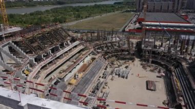 Construction site of stadium near shopping mall in modern city district on riverbank bird eye view. Urban area development