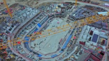 Empty ground inside future sports arena and tower cranes at construction site bird eye view. Urban area development