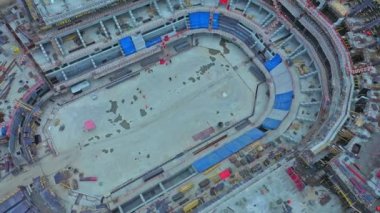 Empty ground inside unfinished sports stadium at construction site in contemporary city bird eye view. Urban development