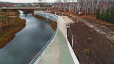 Stylish embankment maintenance on small river bank in park against bridge on autumn day aerial view. Area for recreation