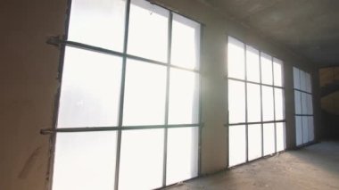 Large windows covered with foil in room of reconstructed building closeup. Restoration of abandoned commercial house