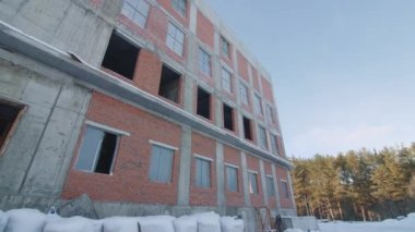 Plastic bags in snowy yard of old brick building under blue sky in winter closeup. Abandoned house at construction site